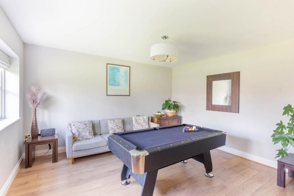 The bright games room at Alnside Lodge, with a pool table and sofa